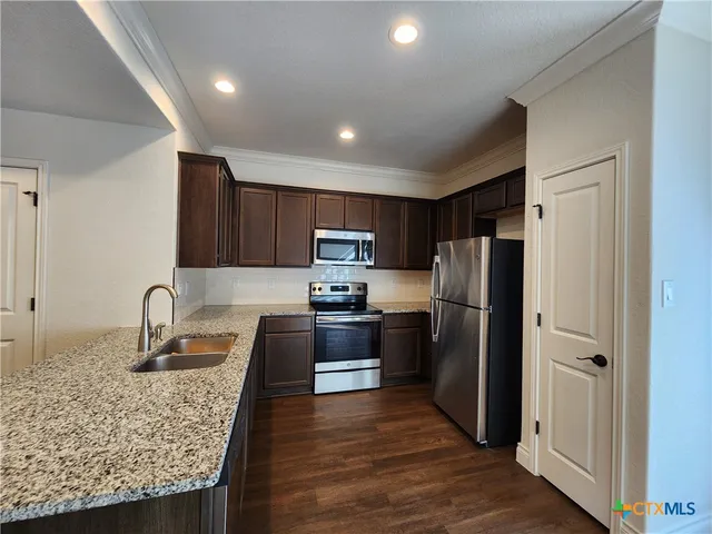 a kitchen with granite countertop stainless steel appliances and wooden cabinets