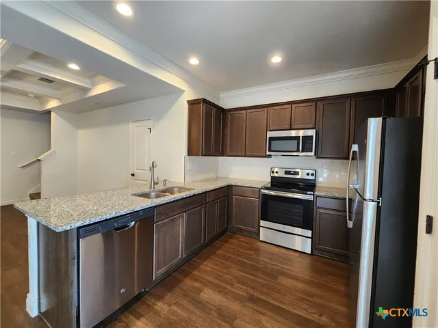 a kitchen with stainless steel appliances granite countertop a sink stove microwave and refrigerator