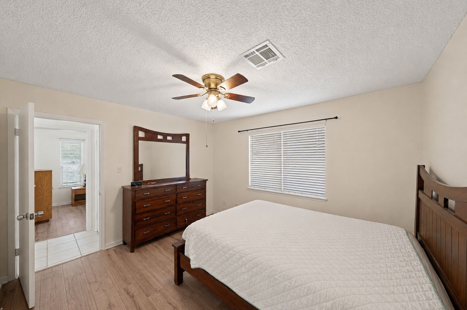 25739 Old Howth Road Hempstead, TX 77445 - Photo 19 of 36 This spacious primary suite provides plenty of room to unwind, with updated wood-look laminate flooring, soft natural light, a cooling ceiling fan and direct access to the updated ensuite bathroom.