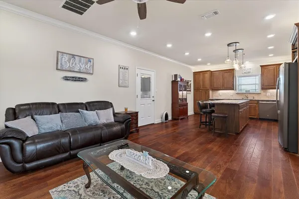 a living room with stainless steel appliances furniture and wooden floor