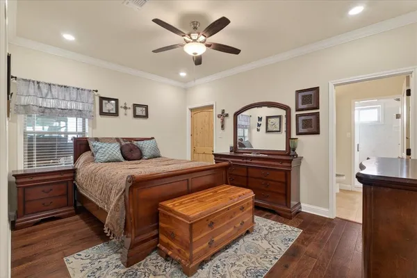 a bedroom with a bed a dresser and potted plants