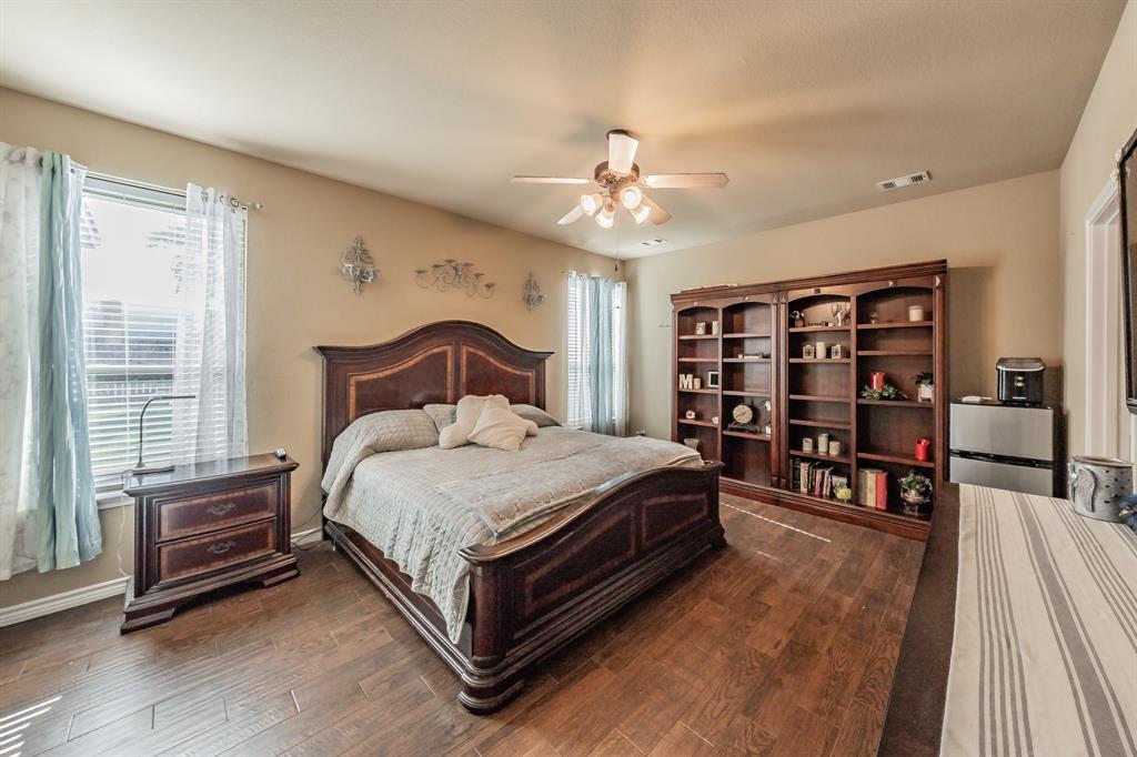 5112 Leeray Road Fort Worth, TX 76244 - Photo 17 of 34 a spacious bedroom with a bed a bookshelf and a bookshelf with wooden floor
