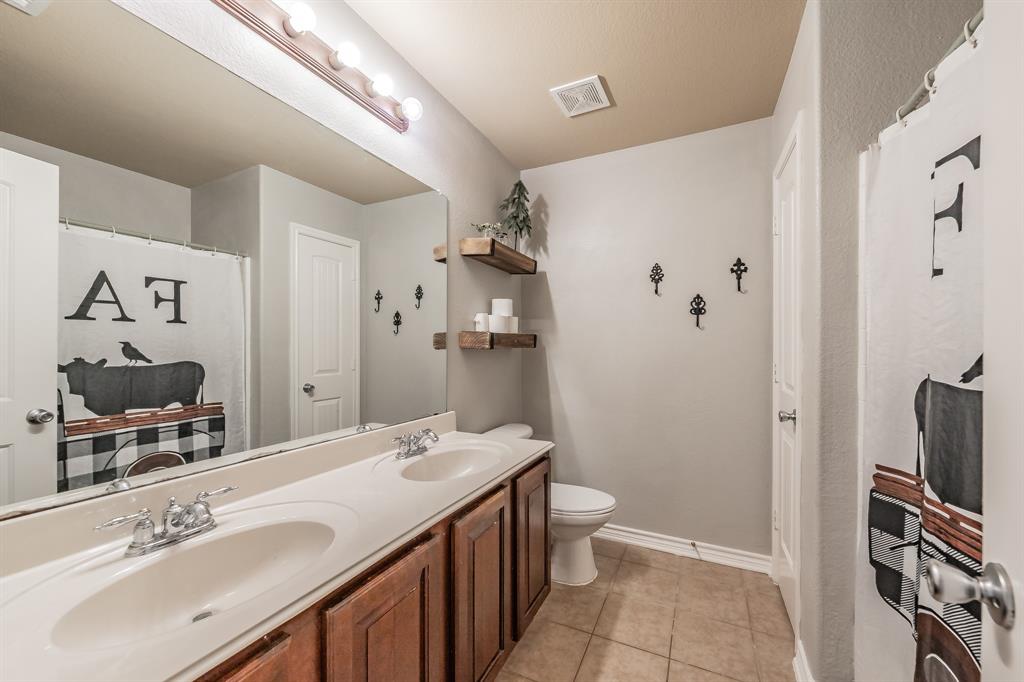 5112 Leeray Road Fort Worth, TX 76244 - Photo 22 of 34 a bathroom with a sink a toilet and a large mirror