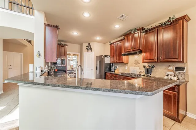 a kitchen with kitchen island granite countertop a sink stove and cabinets