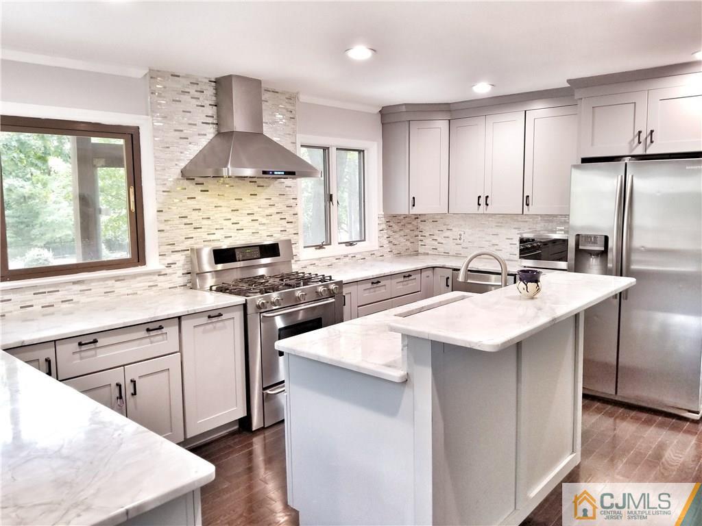 a kitchen with stainless steel appliances granite countertop a sink stove refrigerator and cabinets