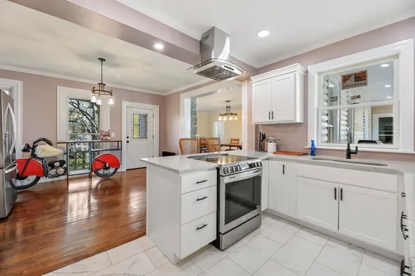 a kitchen with stainless steel appliances granite countertop a stove and white cabinets with wooden floor