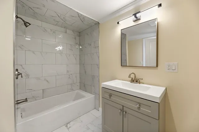 a bathroom with a bathtub shower sink vanity and mirror