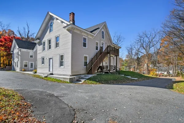 a view of a white house with a big yard and large trees