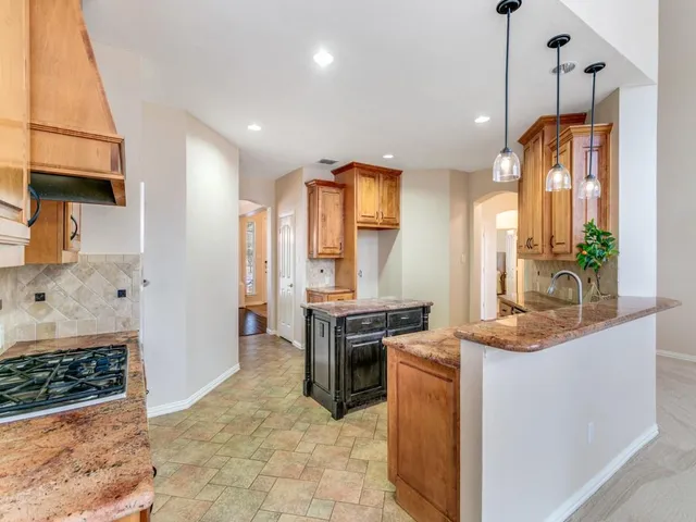 a kitchen with stainless steel appliances granite countertop a stove a sink and a refrigerator