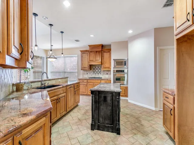 a kitchen with stainless steel appliances granite countertop a sink and a refrigerator