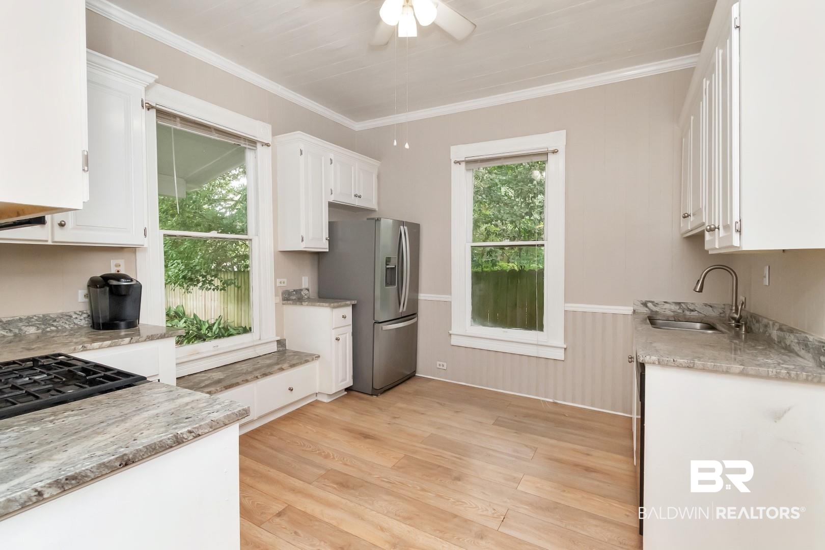 1305 Brown Street Mobile, AL 36604 - Photo 12 of 37 Kitchen with white cabinets, light wood-type flooring, ornamental molding, stainless steel refrigerator with ice dispenser, and sink