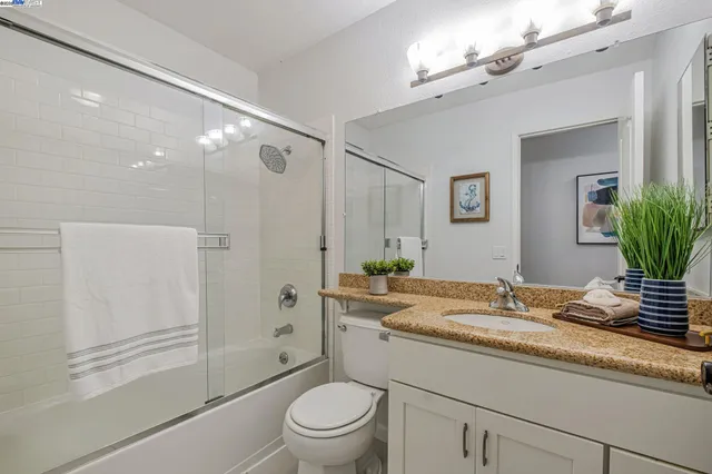 a bathroom with a granite countertop sink toilet a large mirror a shower and a bathtub