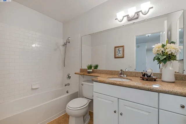 a bathroom with a granite countertop sink a toilet and bathtub