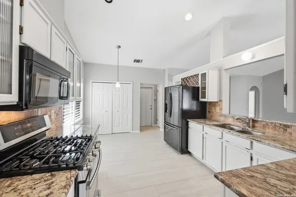 a kitchen with stainless steel appliances granite countertop a refrigerator and a stove top oven