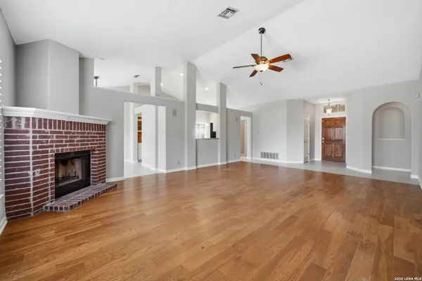 an empty room with windows fireplace and a kitchen view