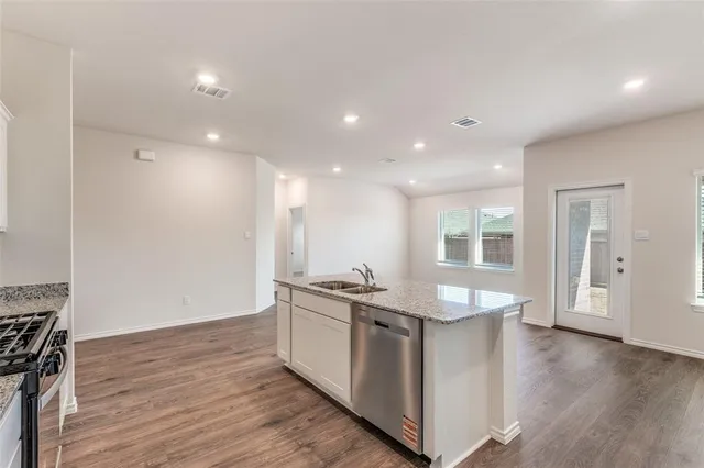 a kitchen with granite countertop a stove a sink and a refrigerator
