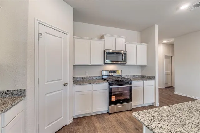 a kitchen with granite countertop a sink and stove top oven