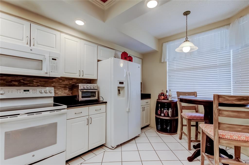 6205 Shoreline Drive, Unit 1304 Seminole, FL 33708 - Photo 5 of 57 a kitchen with stainless steel appliances kitchen island granite countertop a stove a refrigerator and cabinets
