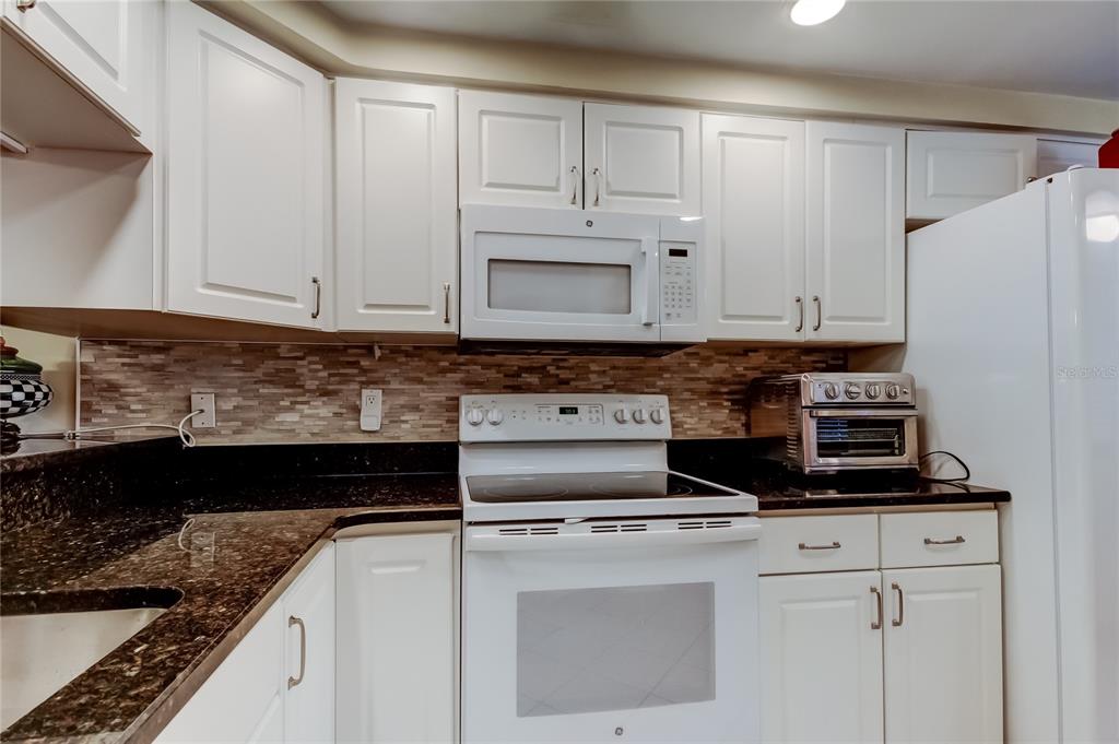 6205 Shoreline Drive, Unit 1304 Seminole, FL 33708 - Photo 6 of 57 a kitchen with stainless steel appliances granite countertop a stove a refrigerator and a white cabinets
