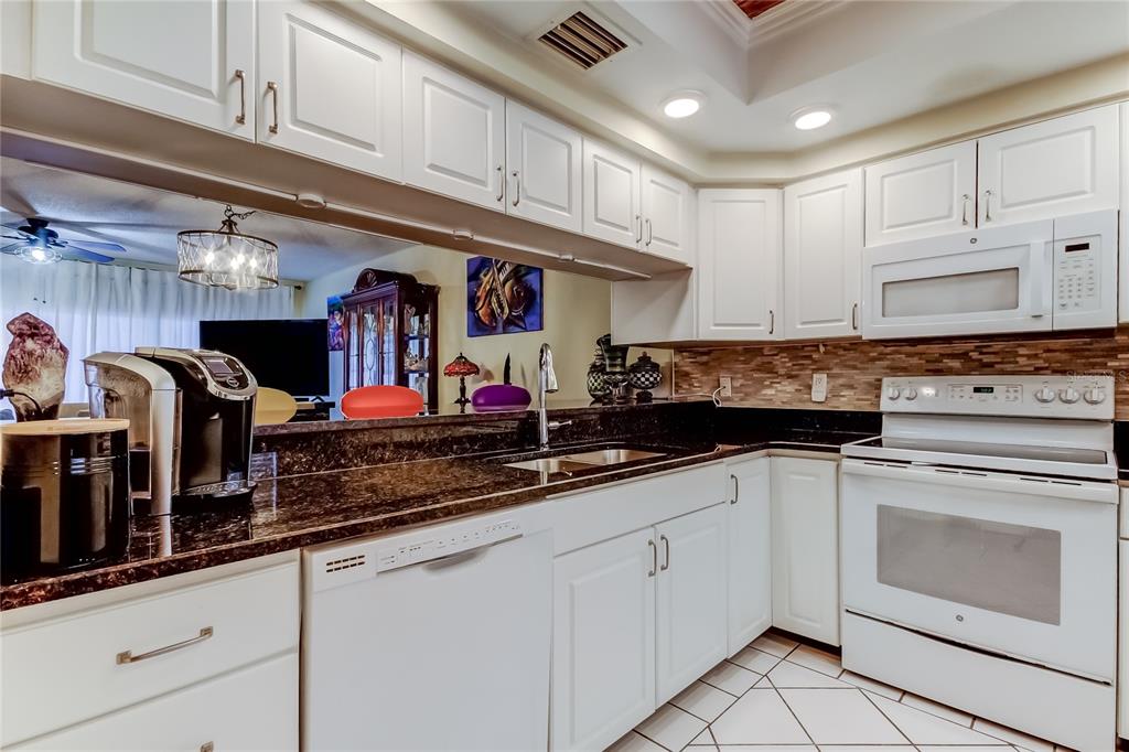 6205 Shoreline Drive, Unit 1304 Seminole, FL 33708 - Photo 10 of 57 a kitchen with stainless steel appliances granite countertop a sink and cabinets
