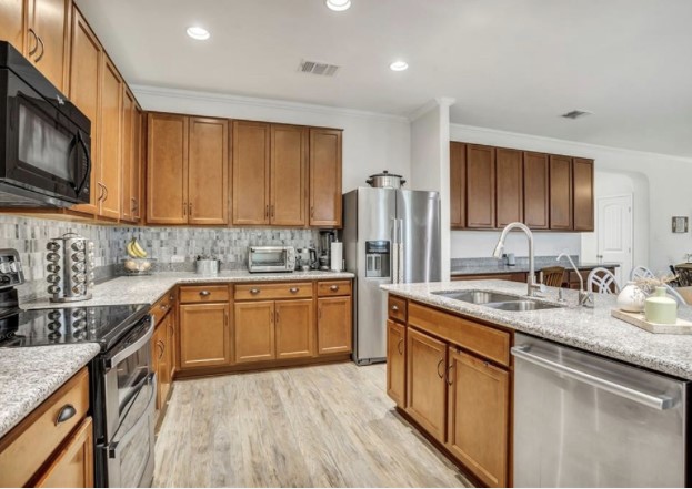 1428 Crested Butte Way Georgetown, TX 78626 - Photo 12 of 28 Kitchen with appliances with stainless steel finishes, brown cabinetry, recessed lighting, and crown molding