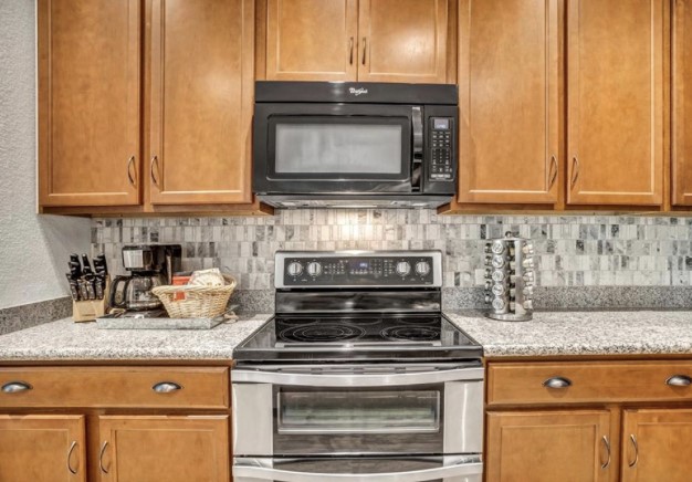 1428 Crested Butte Way Georgetown, TX 78626 - Photo 13 of 28 Kitchen with electric stove, black microwave, decorative backsplash, and brown cabinets