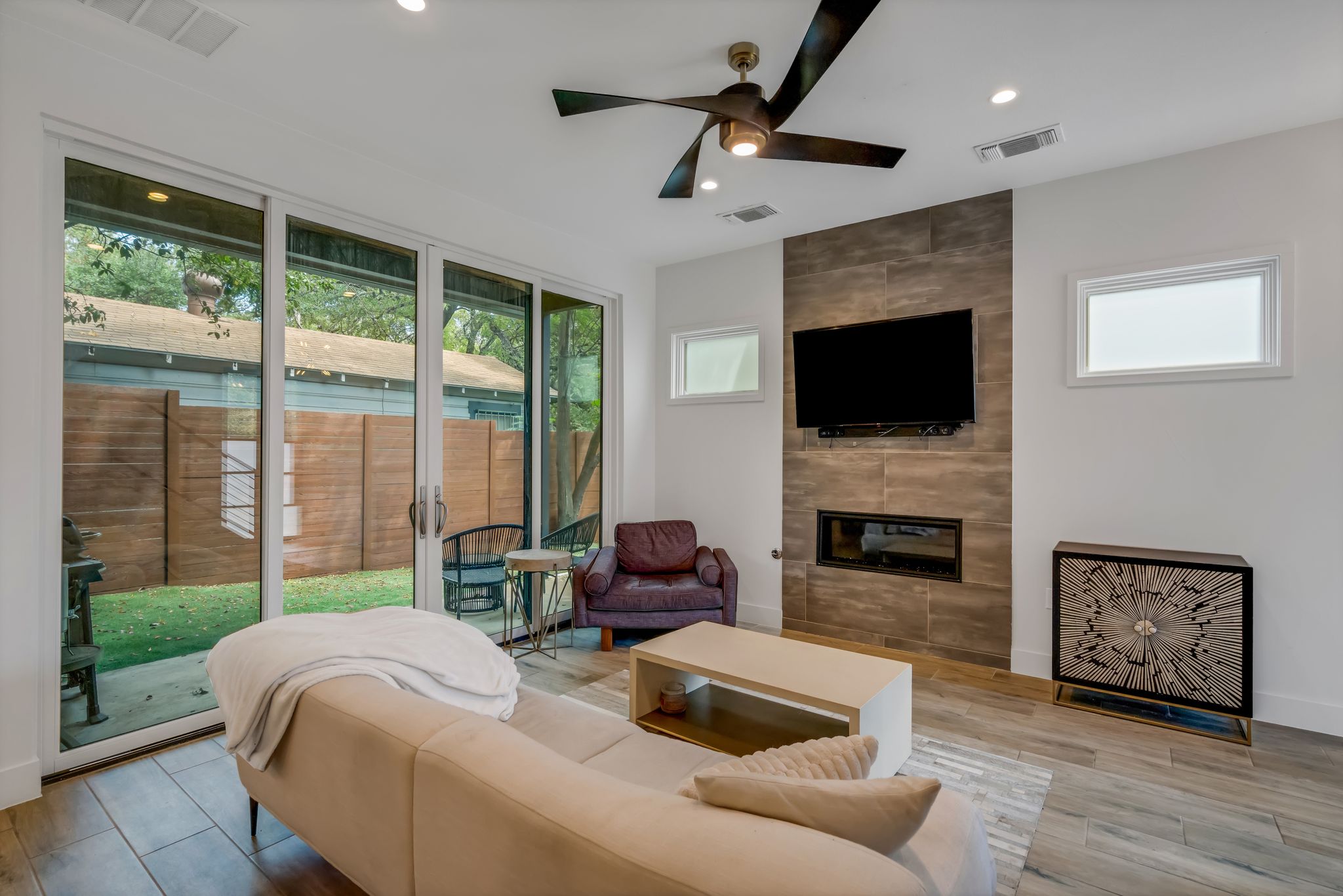 809 Bouldin Avenue Austin, TX 78704 - Photo 31 of 39 Living area featuring a tiled fireplace, light wood-style flooring, a ceiling fan, and recessed lighting