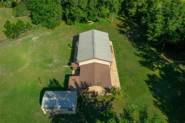 an aerial view of residential house with outdoor space and trees all around