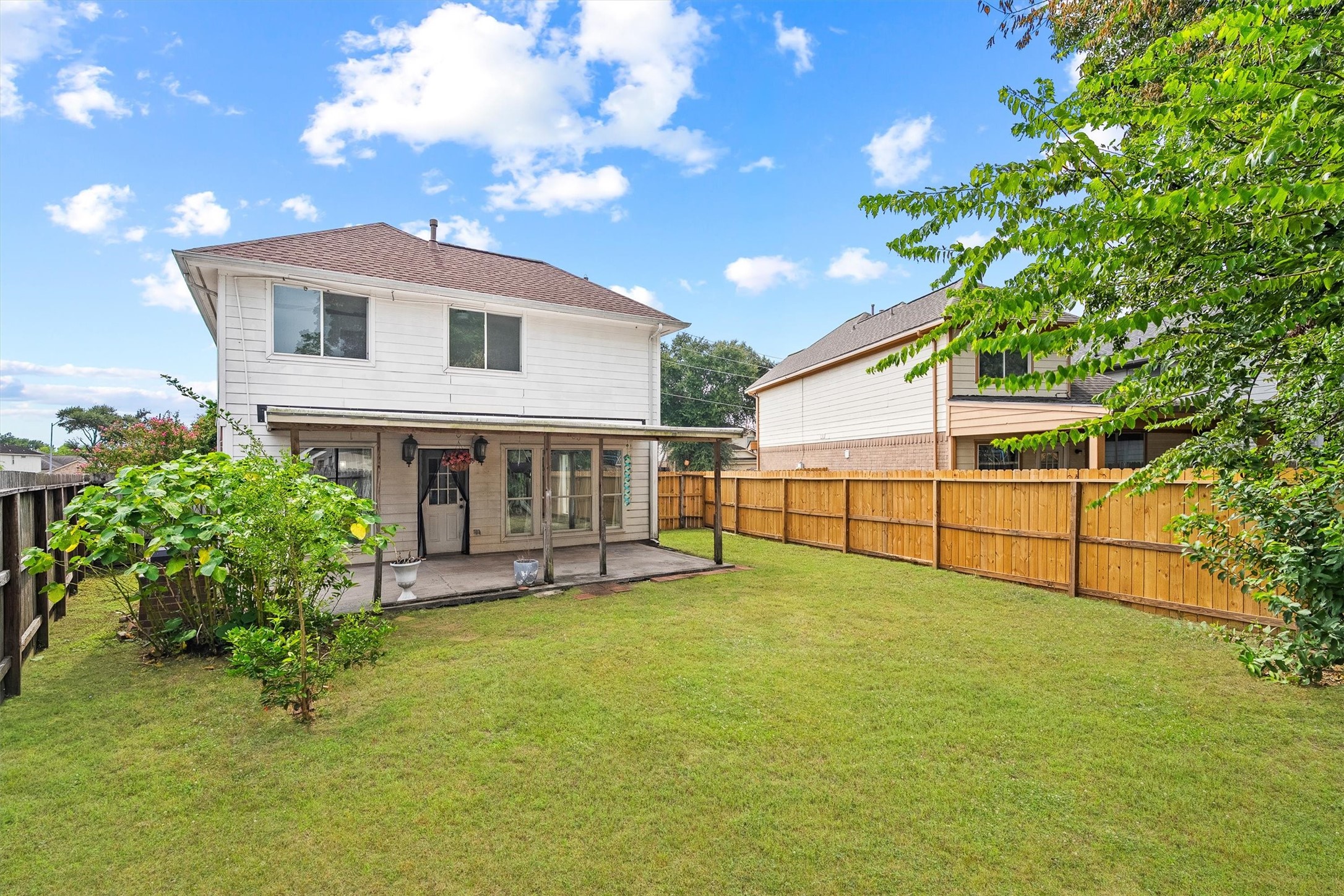 Appealing two-story home with a spacious backyard, featuring a covered patio and lush greenery, perfect for outdoor relaxation and entertaining.