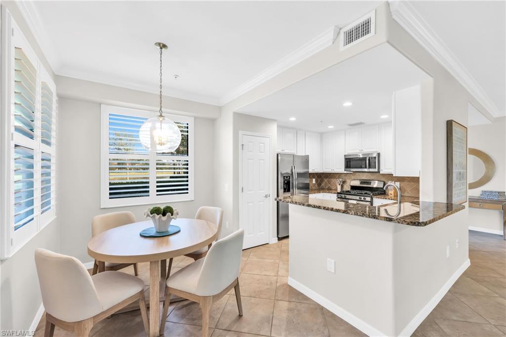 3159 Serena Lane, Unit 102 Naples, FL 34114 - Photo 12 of 42 a kitchen with stainless steel appliances kitchen island granite countertop a dining table and chairs