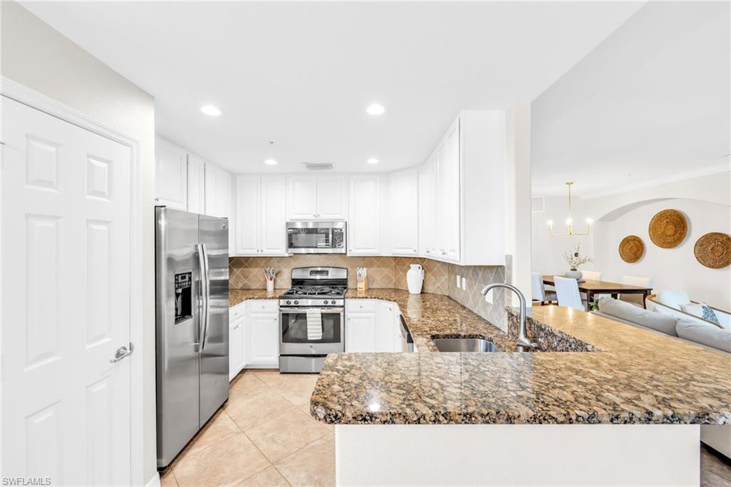 3159 Serena Lane, Unit 102 Naples, FL 34114 - Photo 13 of 42 a kitchen with stainless steel appliances granite countertop a sink stove and refrigerator