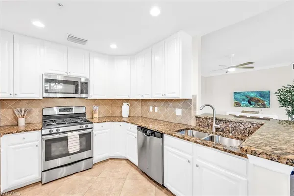 a kitchen with granite countertop a sink stainless steel appliances and white cabinets