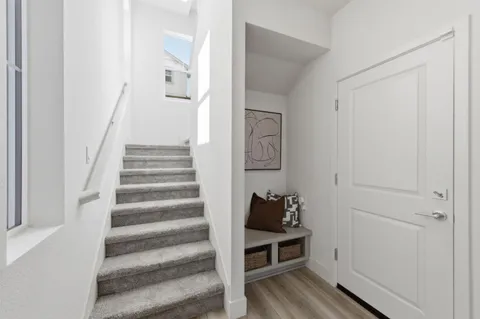 a view of a hallway to a livingroom with wooden floor and furniture