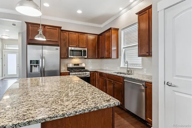 a kitchen with stainless steel appliances granite countertop wooden cabinets a stove top oven a sink and dishwasher