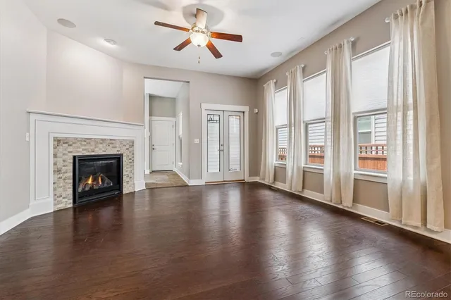 an empty room with wooden floor fireplace and windows