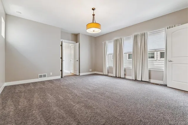 an empty room with chandelier fan and windows