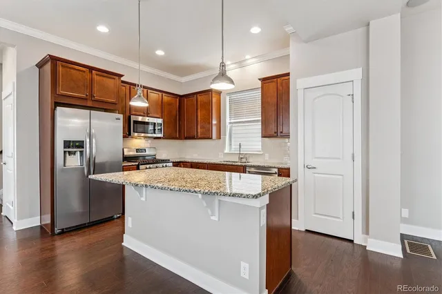 a kitchen with stainless steel appliances granite countertop a refrigerator a sink and a stove