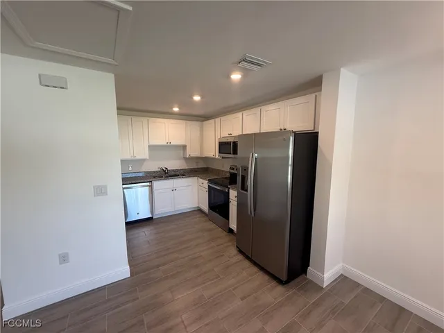 a kitchen with stainless steel appliances granite countertop a refrigerator a sink a stove a microwave and wooden floor