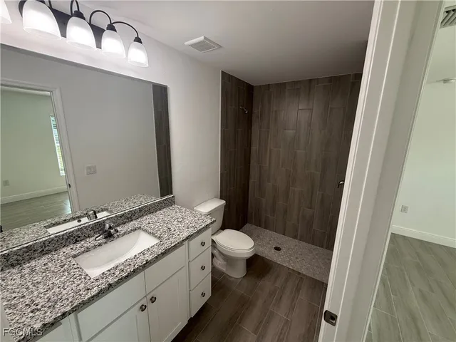 a bathroom with a granite countertop sink toilet and shower