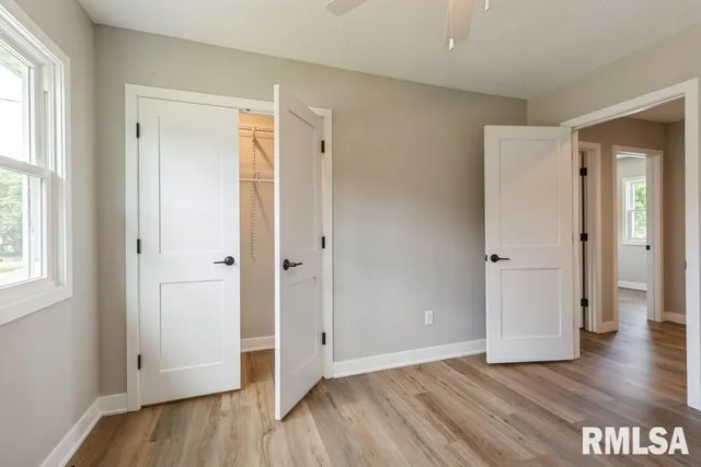a view of an empty room with wooden floor and window