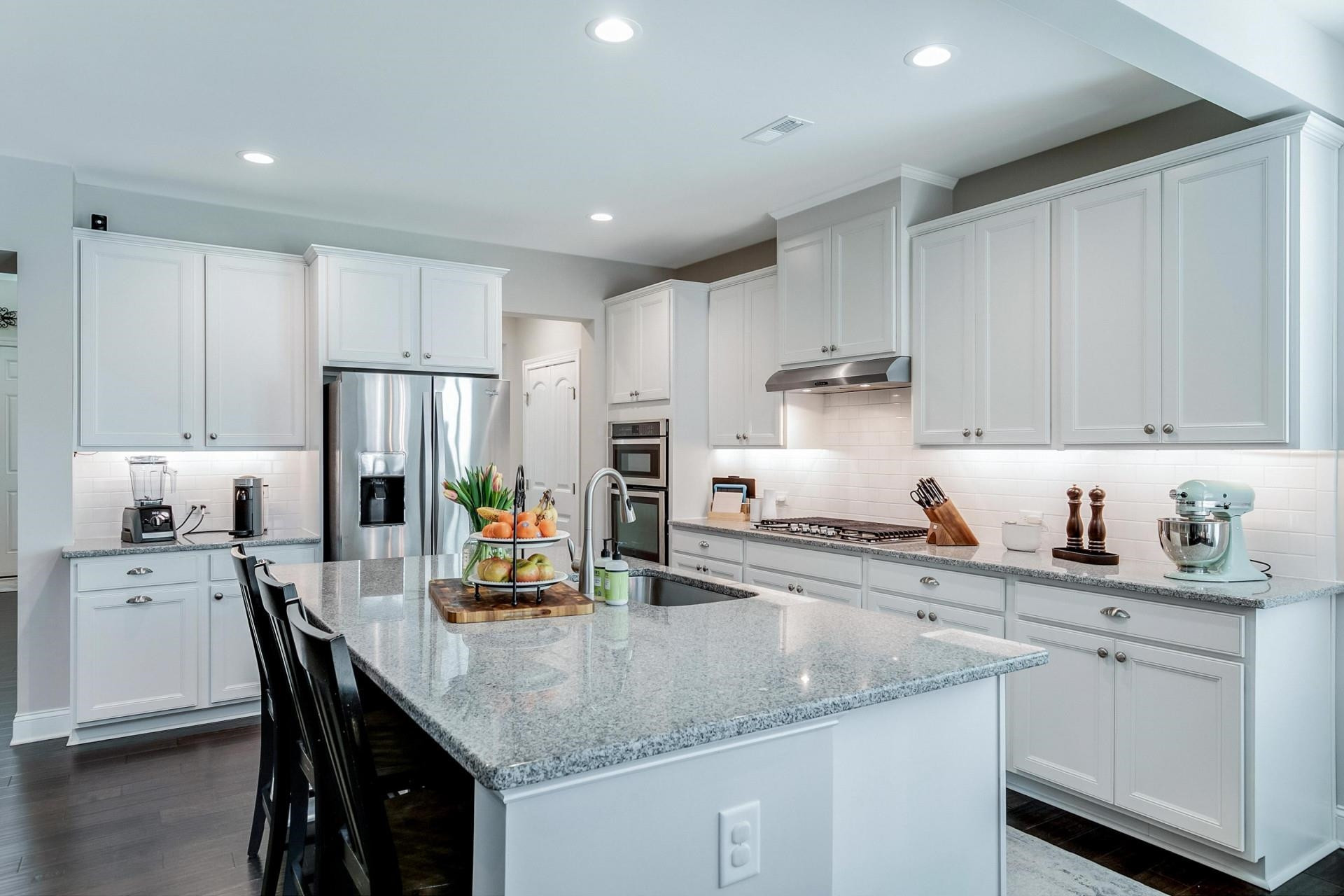 1016 Capstone Drive Durham, NC 27713 - Photo 9 of 50 a kitchen with a sink a stove a refrigerator and white cabinets with wooden floor