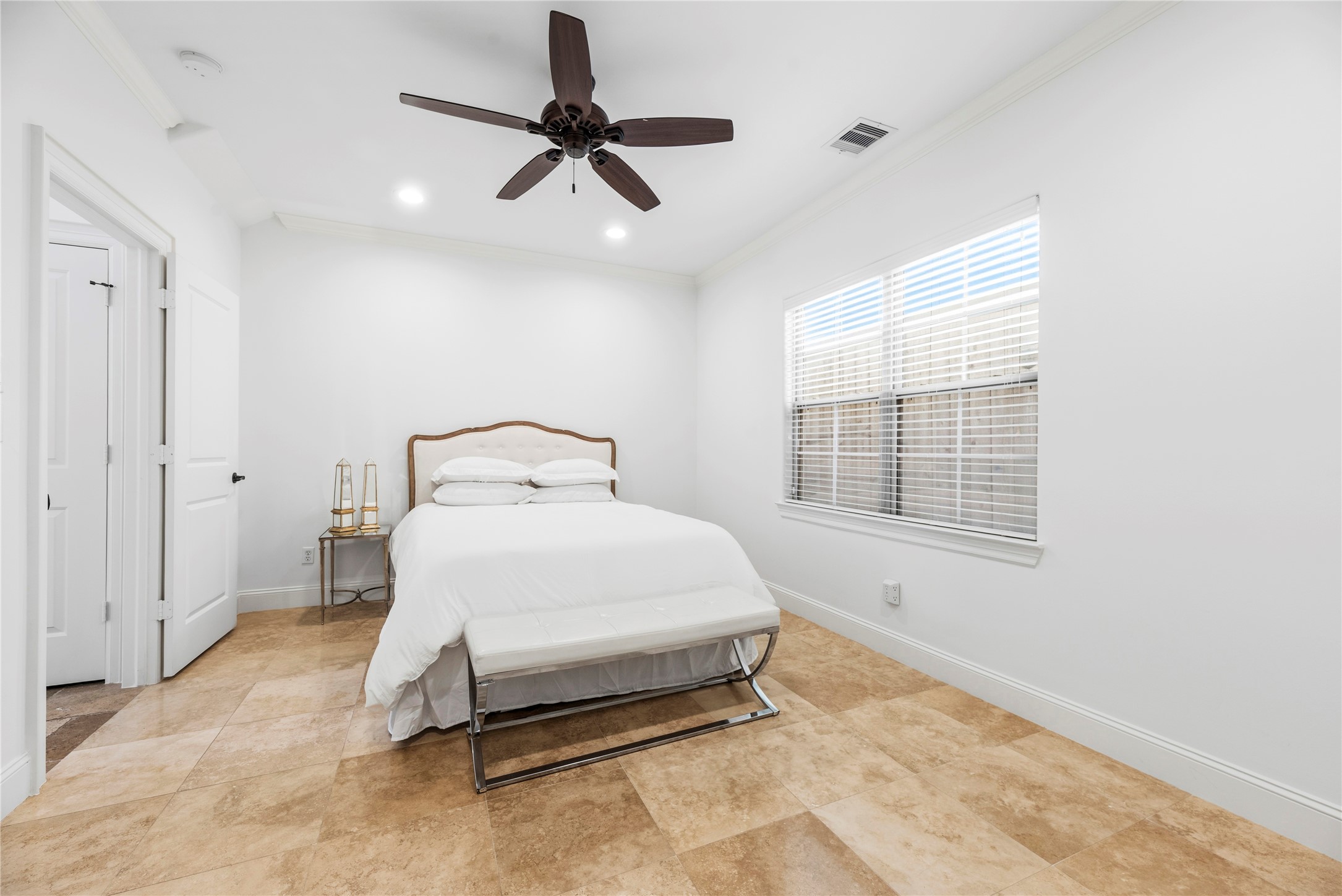 1537 Haddon Street Houston, TX 77006 - Photo 26 of 48 Third bedroom (on first floor) features a cozy layout with neutral tones, tiled flooring, and ample natural light from a large window. It includes a ceiling fan, and an adjacent en-suite bathroom.