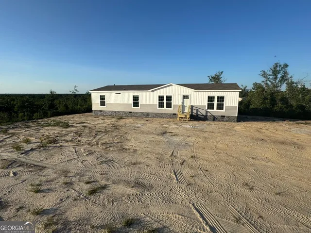 a view of house with yard and trees in the background