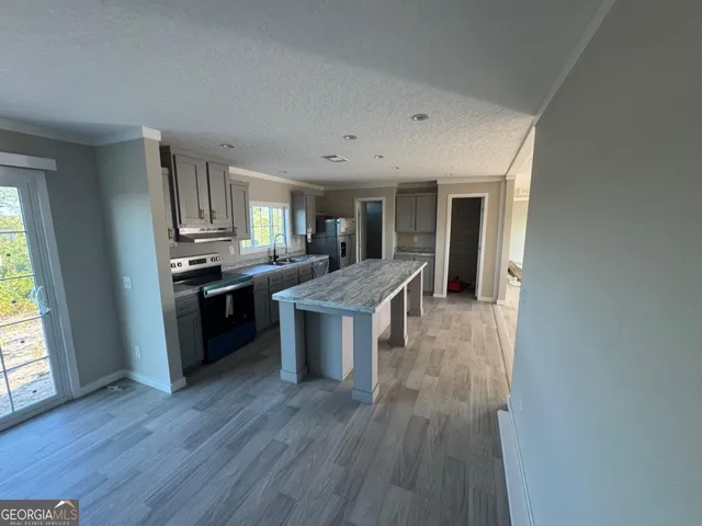 a kitchen with stainless steel appliances kitchen island wooden floors and white walls