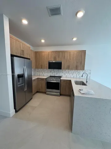 a kitchen with granite countertop a refrigerator and a sink