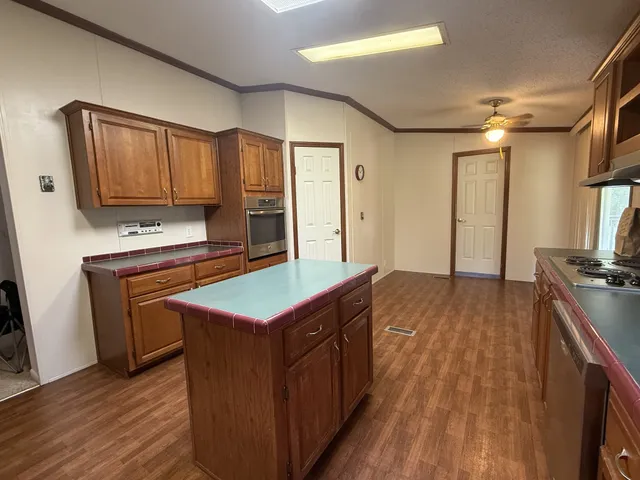 a kitchen with kitchen island granite countertop wooden cabinets a sink and a stove
