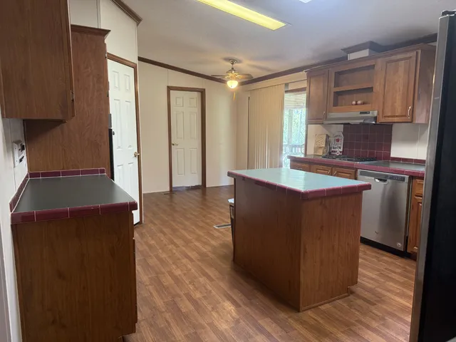 a kitchen with stainless steel appliances granite countertop a stove a refrigerator a sink and dishwasher with wooden floor