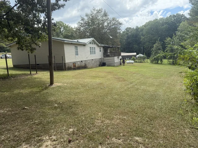 a view of a house with backyard and trees