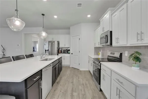 a kitchen with stainless steel appliances kitchen island granite countertop a sink a stove top oven a counter space and cabinets