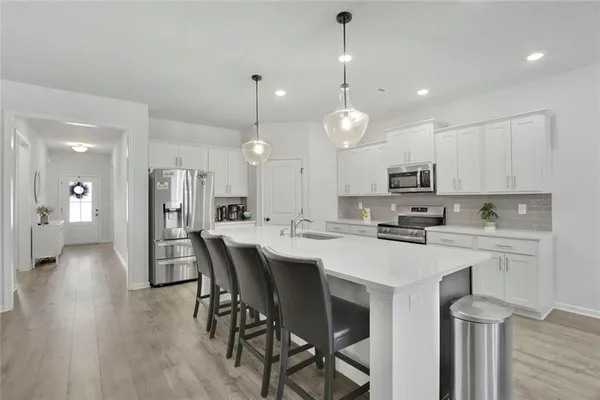 a kitchen with stainless steel appliances stove refrigerator dining table and chairs